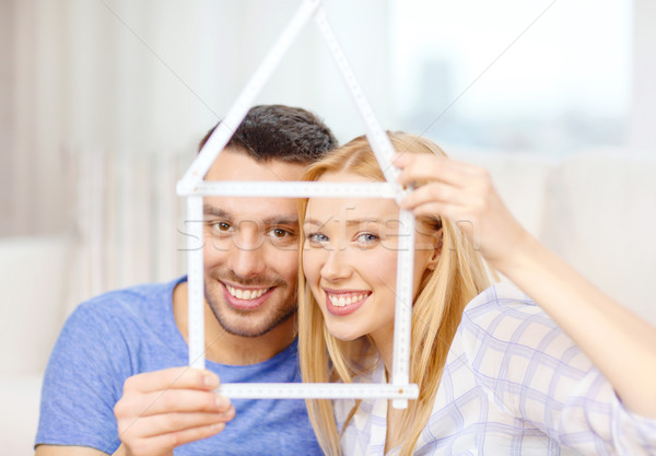 smiling couple with house from measuring tape Stock photo © dolgachov