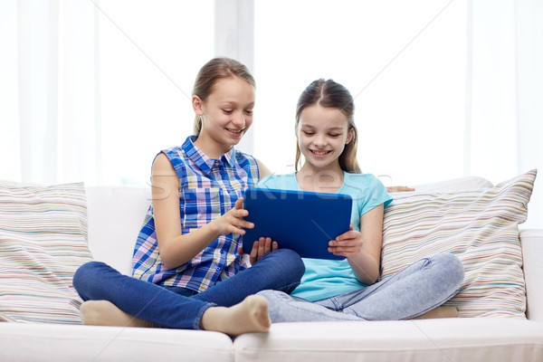 happy girls with tablet pc sitting on sofa at home Stock photo © dolgachov