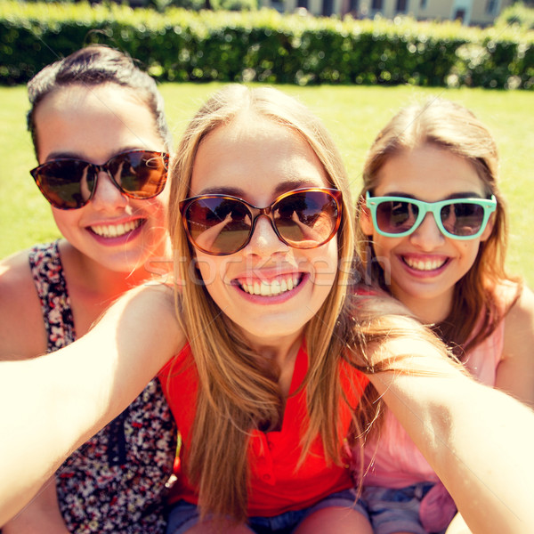 Stock photo: group of smiling teen girls taking selfie in park