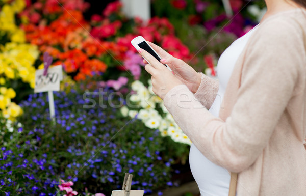 Stock photo: pregnant woman with smartphone at flower market