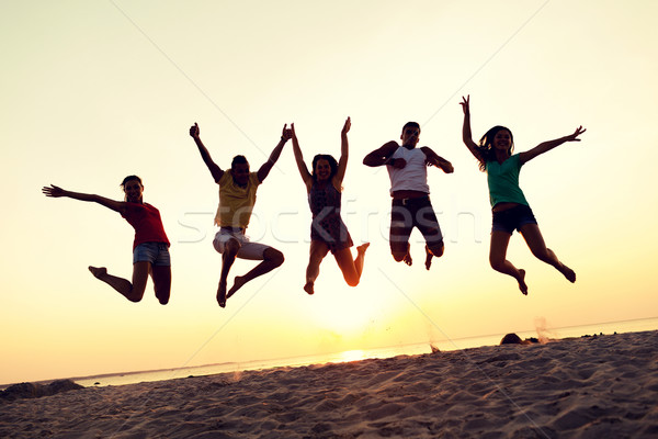 smiling friends dancing and jumping on beach Stock photo © dolgachov