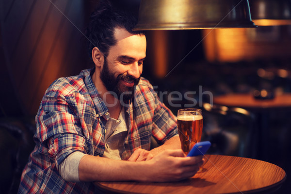 man with smartphone and beer texting at bar Stock photo © dolgachov