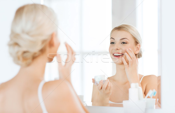 Heureux femme crème visage salle de bain [[stock_photo]] © dolgachov