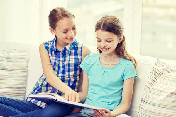 two happy girls reading book at home Stock photo © dolgachov