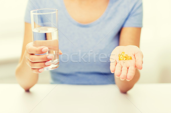 close up of woman hands with capsules and water Stock photo © dolgachov