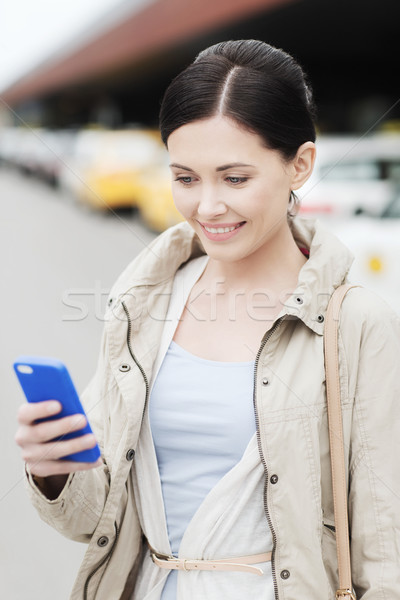smiling woman with smartphone over taxi in city Stock photo © dolgachov