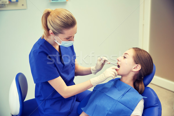 female dentist checking patient girl teeth Stock photo © dolgachov
