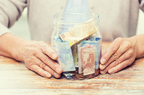 close up of senior woman with money in glass jar Stock photo © dolgachov