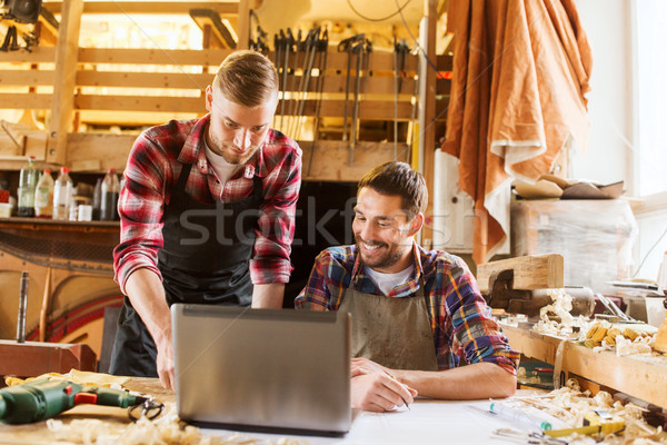 carpenters with laptop and blueprint at workshop Stock photo © dolgachov