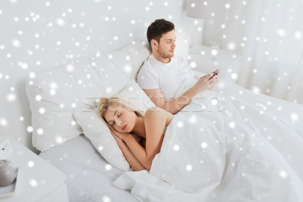 man texting message while woman is sleeping in bed Stock photo © dolgachov