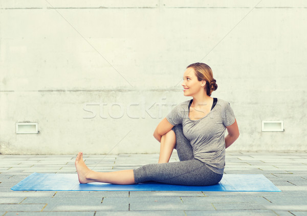woman making yoga in twist pose on mat Stock photo © dolgachov
