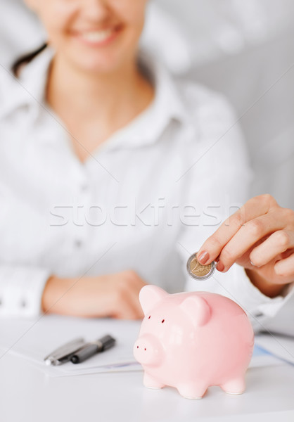 Stock photo: woman hand putting coin into small piggy bank