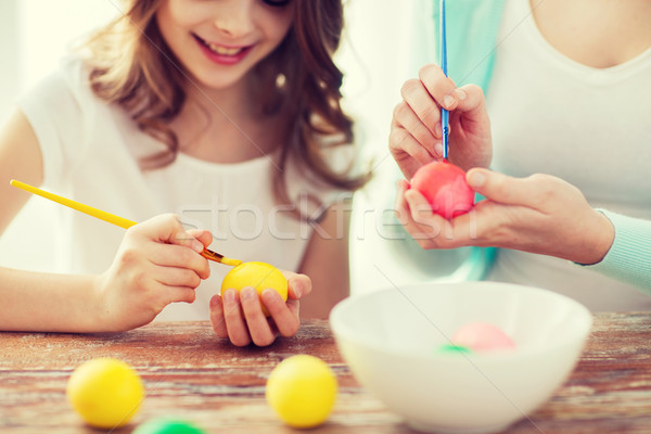close up of little girl and mother coloring eggs Stock photo © dolgachov