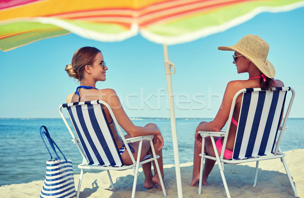 happy women sunbathing in lounges on beach Stock photo © dolgachov