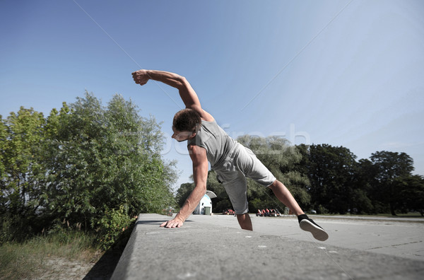 sporty young man jumping in summer park Stock photo © dolgachov