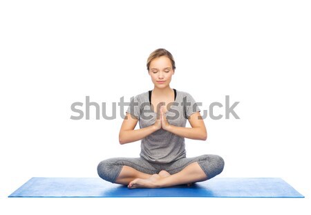 woman making yoga meditation in lotus pose on mat Stock photo © dolgachov