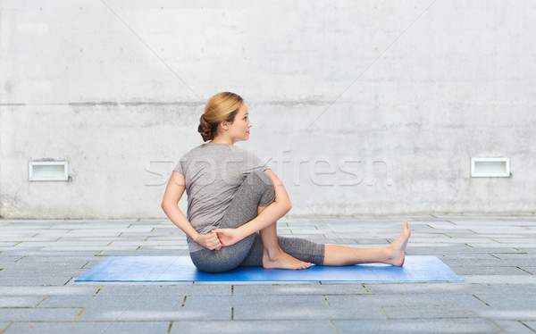 Stock photo: woman making yoga in twist pose on mat outdoors