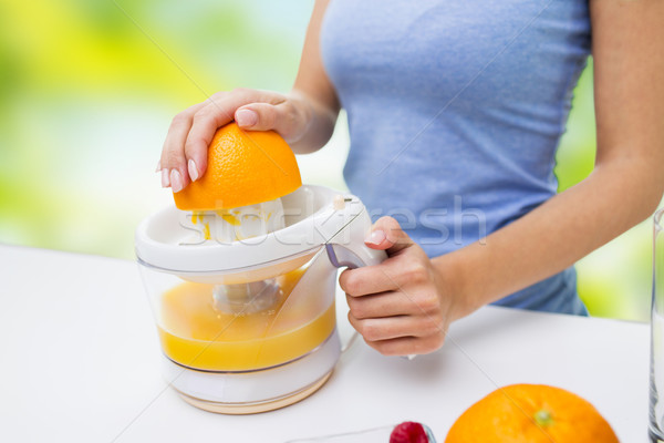 close up of woman squeezing orange juice at home Stock photo © dolgachov