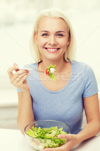 Stock photo: smiling young woman eating salad at home