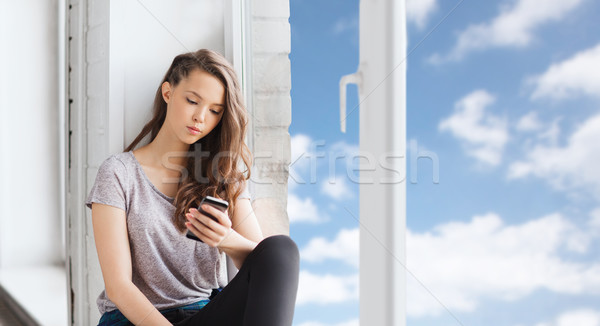 sad pretty teenage girl with smartphone texting Stock photo © dolgachov