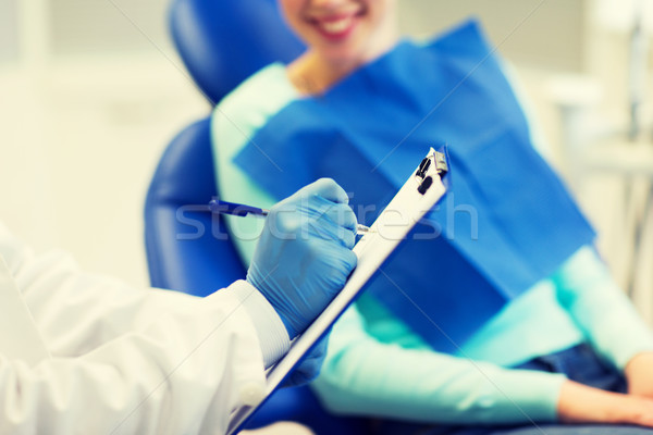 close up of dentist with clipboard and patient Stock photo © dolgachov