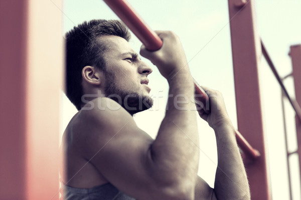 young man exercising on horizontal bar outdoors Stock photo © dolgachov