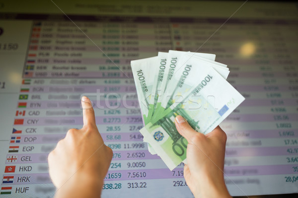 hands with euro money over currency exchange rates Stock photo © dolgachov