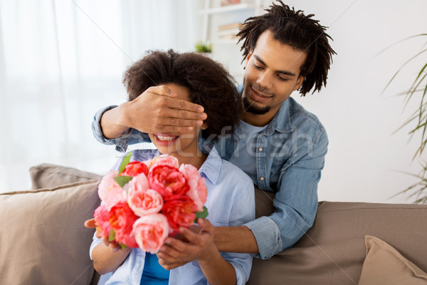 Stock photo: happy couple with bunch of flowers at home