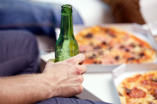 Stock photo: man with beer bottle and pizza at home