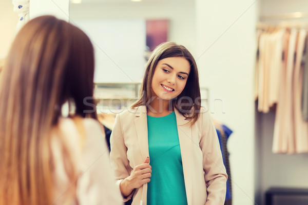 happy woman posing at mirror in clothing store Stock photo © dolgachov