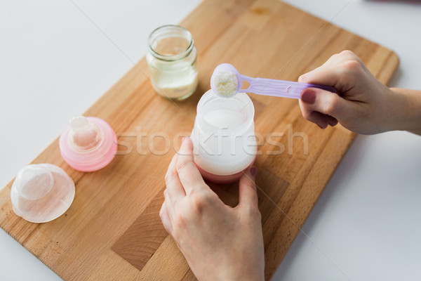 hands with bottle and scoop making formula milk Stock photo © dolgachov