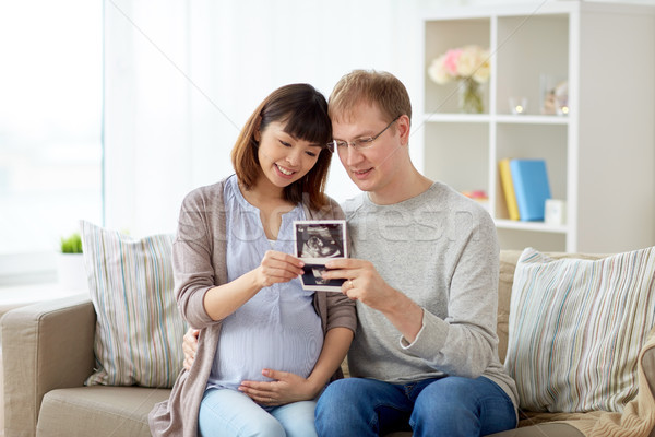 Stock photo: happy couple with ultrasound images at home