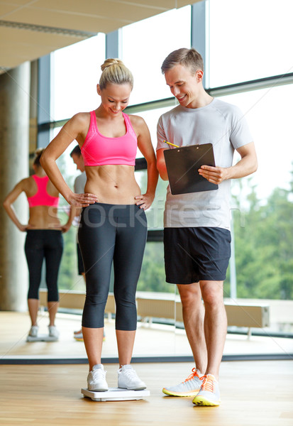 smiling man and woman with scales in gym Stock photo © dolgachov