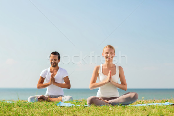 Stock photo: smiling couple making yoga exercises outdoors