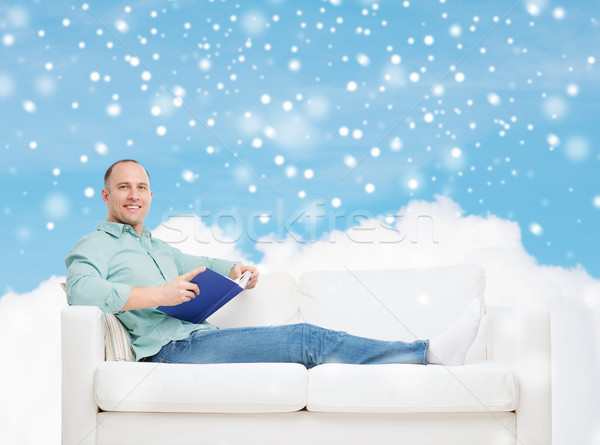 Stock photo: smiling man with book lying on sofa