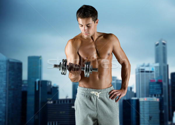 Stock photo: young man with dumbbell flexing biceps