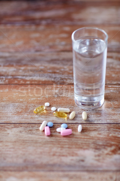pills and capsules with glass of water on table Stock photo © dolgachov