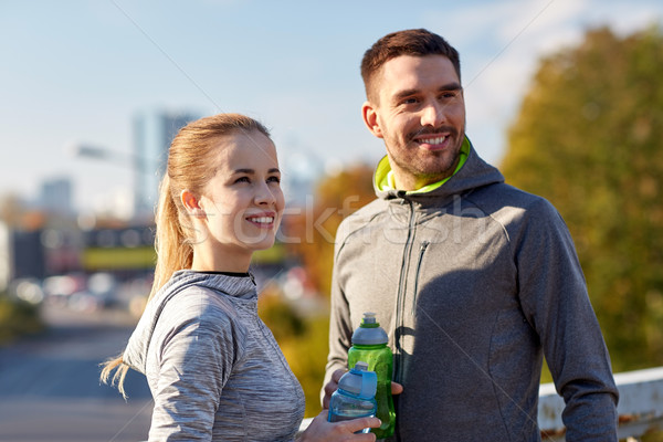 smiling couple with bottles of water outdoors Stock photo © dolgachov