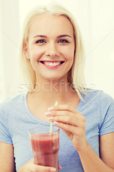 Stock photo: smiling woman drinking juice or shake at home