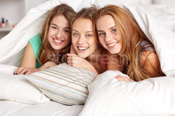 happy young women in bed at home pajama party Stock photo © dolgachov