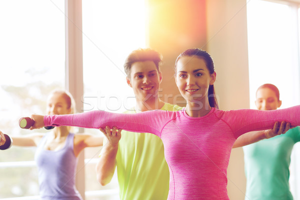 Groupe souriant personnes travaillant sur haltères fitness [[stock_photo]] © dolgachov