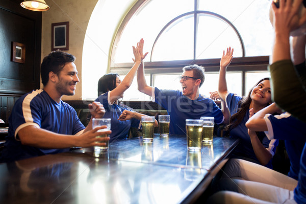 football fans with beer celebrating victory at bar Stock photo © dolgachov