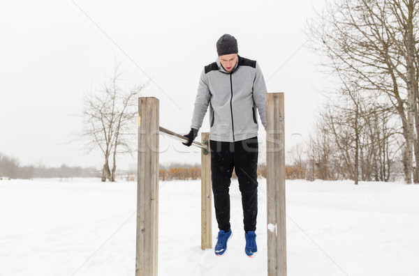 young man exercising on parallel bars in winter Stock photo © dolgachov