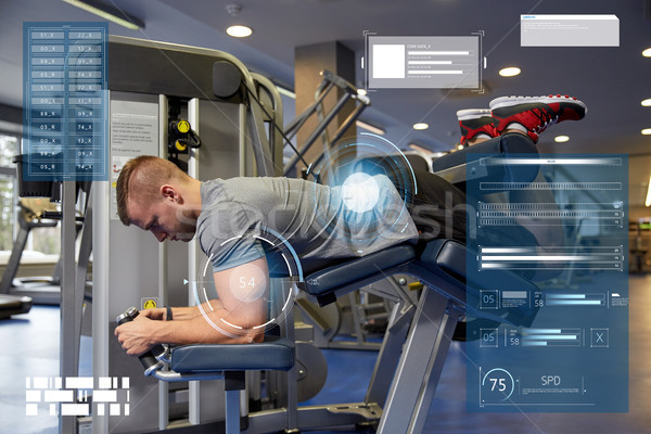 Stock photo: man flexing leg muscles on gym machine