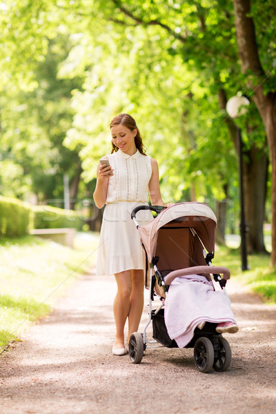 happy mother with smartphone and stroller at park Stock photo © dolgachov
