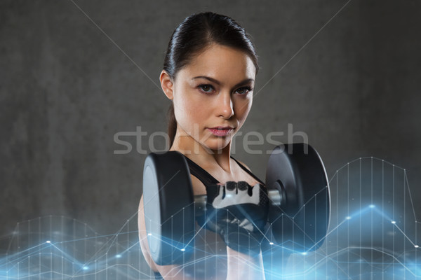 young woman flexing muscles with dumbbells in gym Stock photo © dolgachov