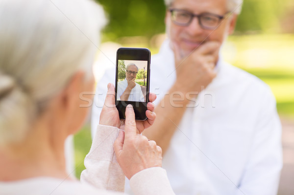 old woman photographing man by smartphone in park Stock photo © dolgachov