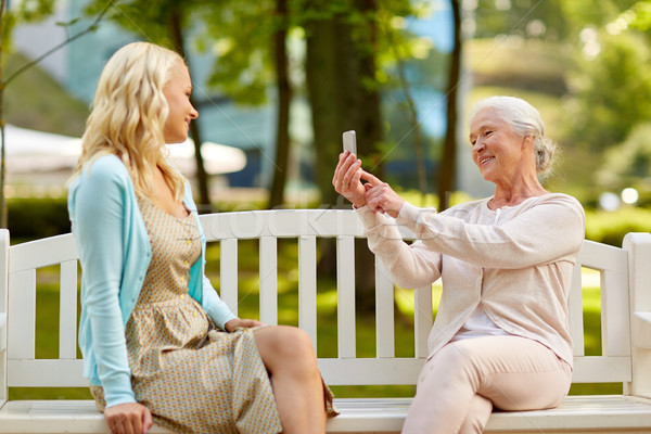 Stock photo: senior mother photographing daughter by smartphone