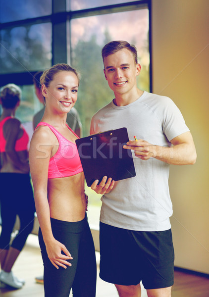 smiling young woman with personal trainer in gym Stock photo © dolgachov