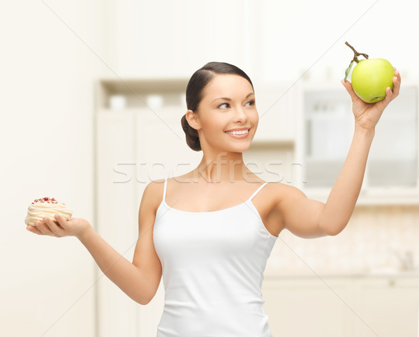 sporty woman with apple and cake in kitchen Stock photo © dolgachov